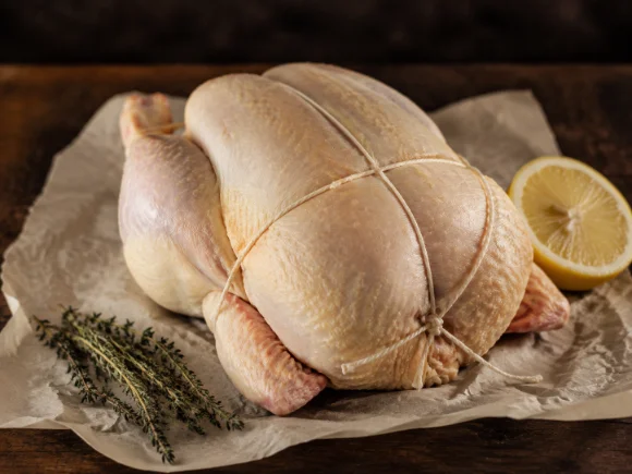 Poulet fermier entier cru, bridé, sur papier sulfurisé